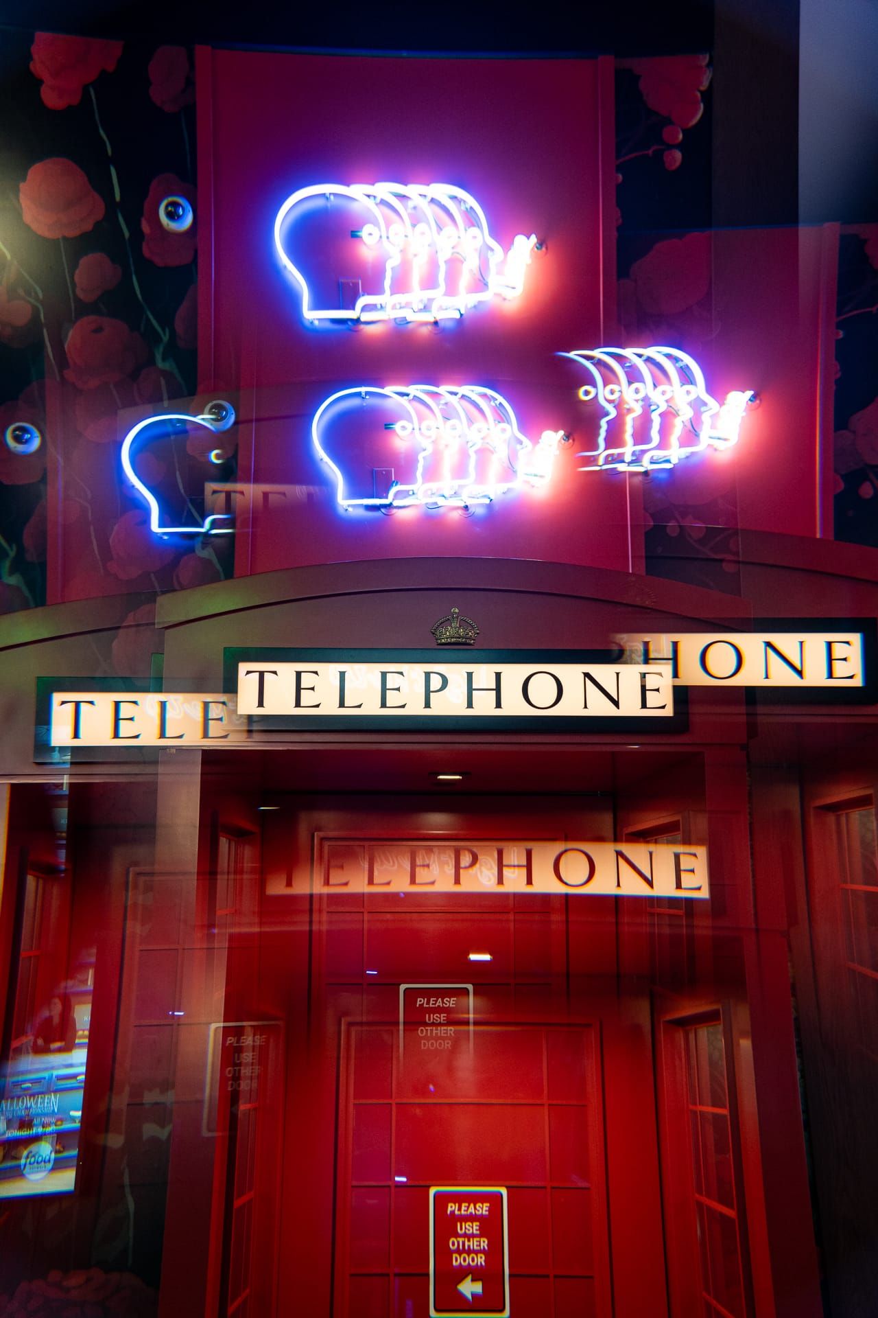 Neon signs above the red telephone booth door at DAZED!